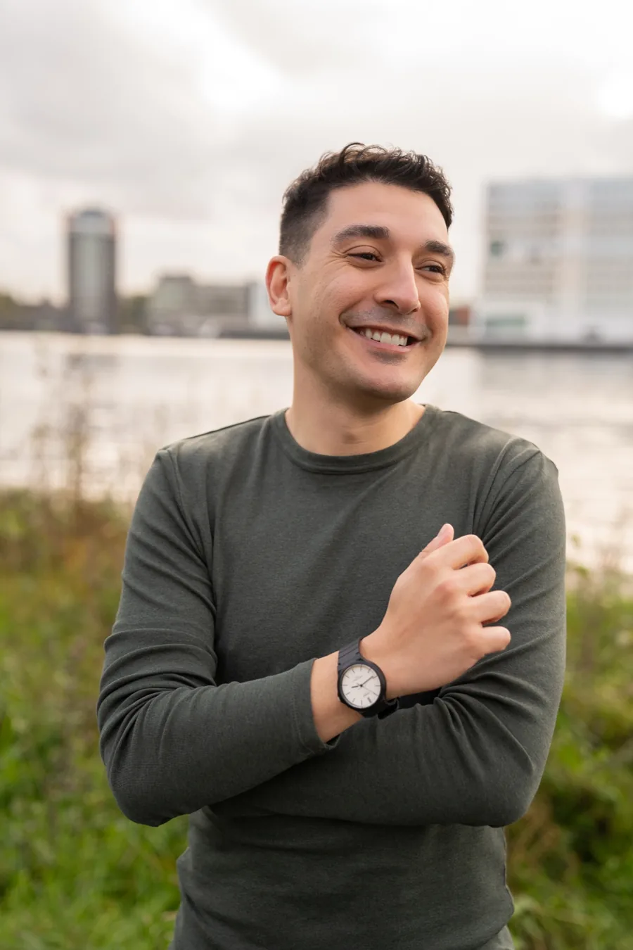 Luis Fernando Romero Calero in a green sweater, smiling, by the water in Amsterdam